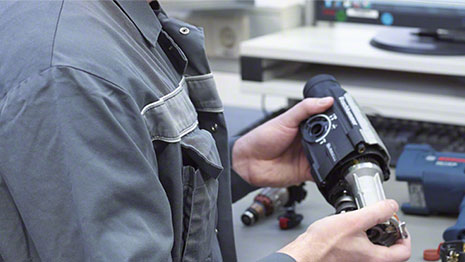 Seorang pria memegang alat hitam Bosch Professional di tangannya.