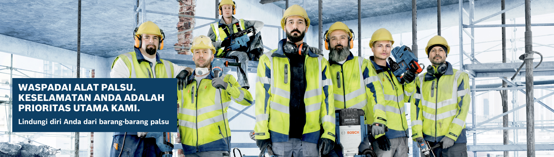 Enam pekerja dengan jaket keselamatan kuning dan helm berdiri di atas perancah.