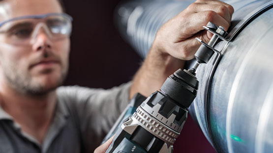 Seorang pengrajin menggunakan bor nirkabel Bosch Professional pada pipa.