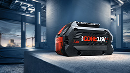 Baterai Bosch Professional CORE 18V diletakkan di atas permukaan abu-abu.