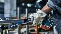 Sebuah gerinda sudut nirkabel Bosch Professional dipegang dengan satu tangan.