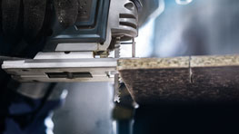 Sebuah gergaji Bosch Professional memotong papan kayu.