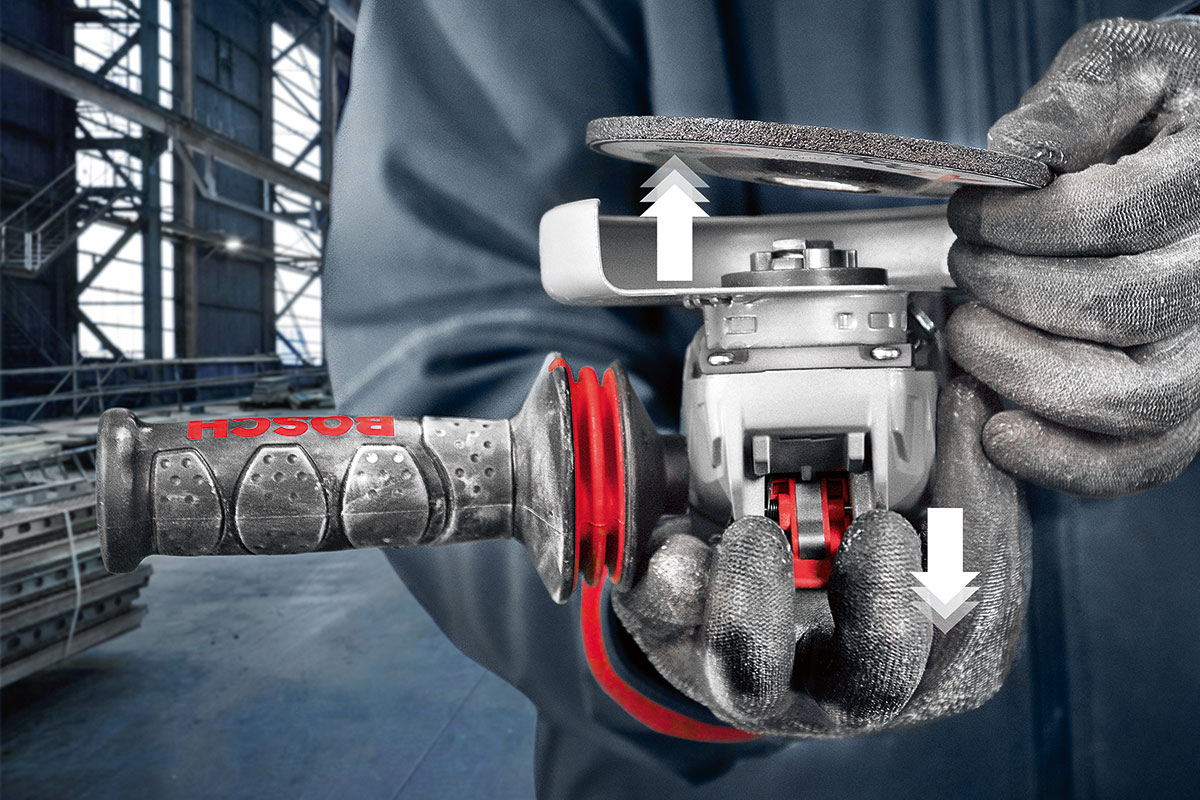 Dua tangan memegang mesin pengamplasan Bosch Professional di sebuah bengkel.