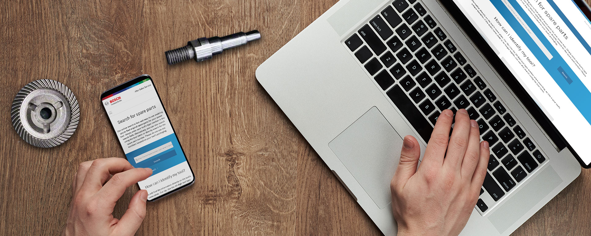 Sebuah tangan mengoperasikan laptop dan smartphone dengan situs web Bosch.